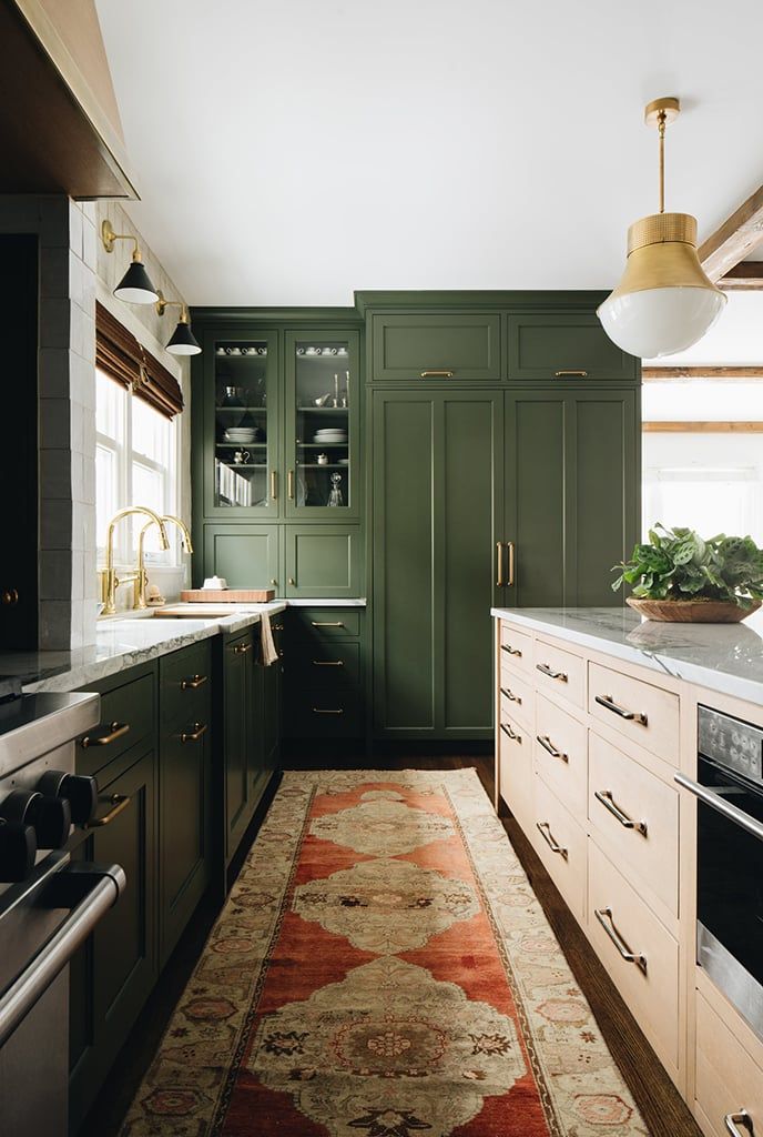 a kitchen with green cabinets and an area rug