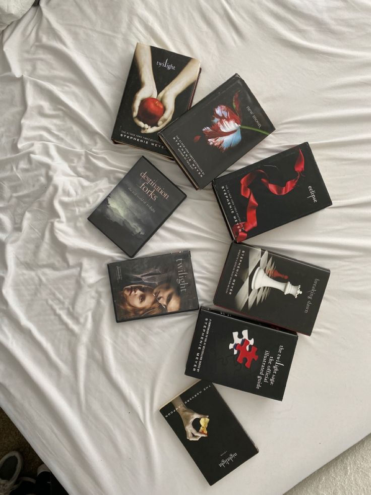 six books are laying on top of a white bed with the covers pulled back and folded down