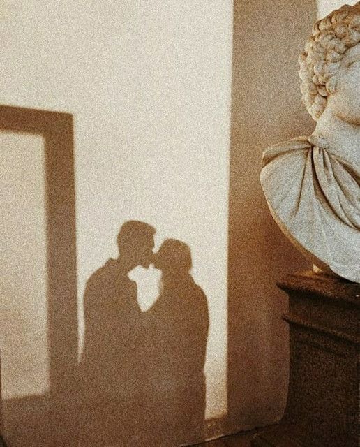 the shadow of two people standing next to a busturine with their arms around each other