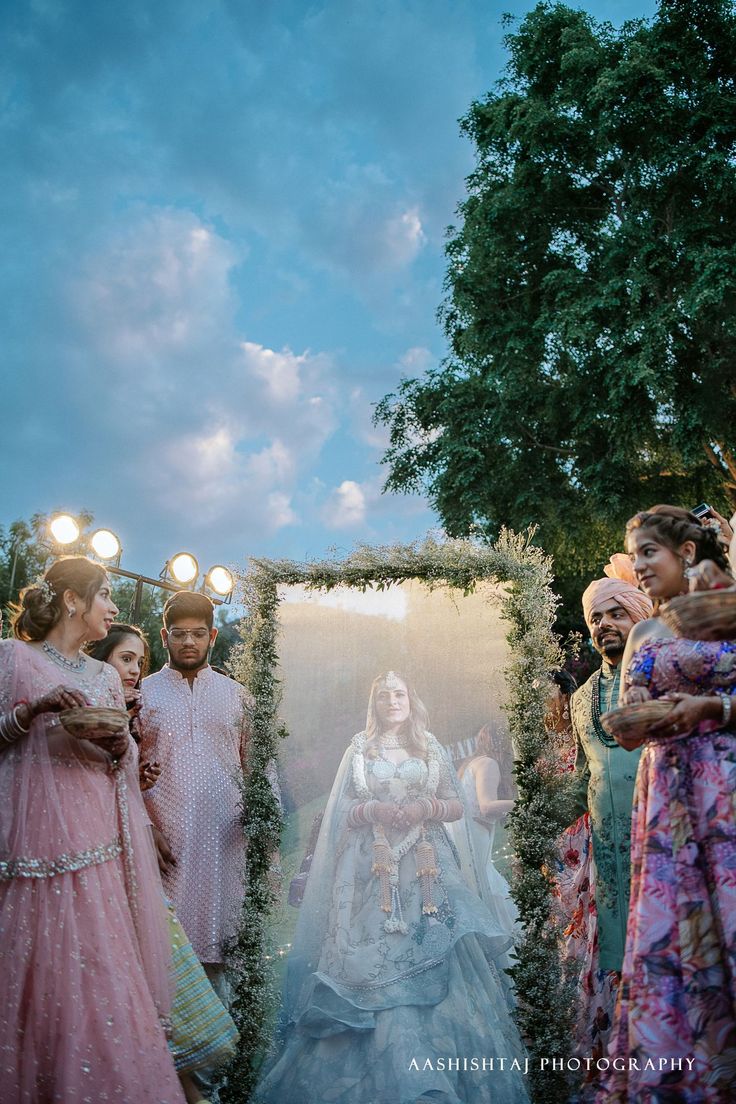 a group of people standing around each other in front of a frame with a woman wearing a wedding dress