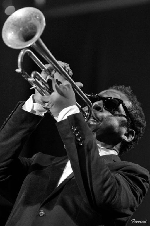 a man in a suit and sunglasses playing a trumpet