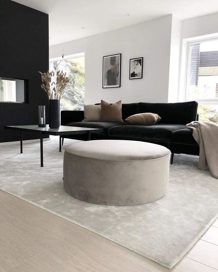 a living room filled with furniture and a large round ottoman on top of a rug