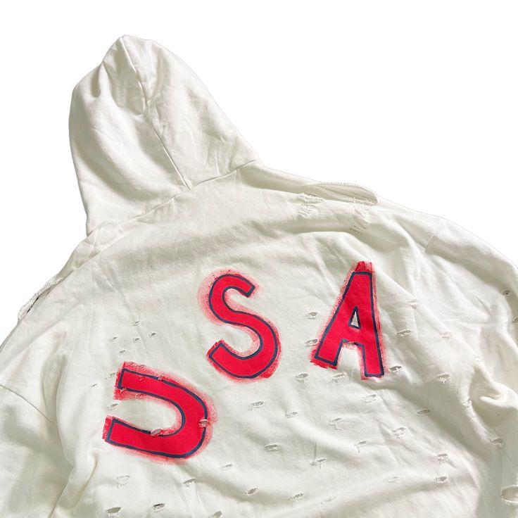 DESCRIPTION EACH PIECE IS MADE TO ORDER, HAND PAINTED BY GLORIA AND HER TEAM IN THEIR NYC STUDIO PRODUCT DESCRIPTION The perfect oversized white distressed hoodie. American flag painted on front chest, with USA painted on back in red, with blue outline. Signed @wrenandglory Due to each piece being hand painted, each piece might have slight differences. Limited edition. FIT Oversized, Super Comfy, Slouchy fit. Can be worn as a sweater or dress. One size fits most Measurements: Body Width 27", Len White Distressed Casual Sweatshirt, Sporty Distressed White Tops, White Distressed Sweatshirt For Fall, White Distressed Tops For Streetwear, Sporty Long Sleeve Distressed Hoodie, 4th Of July Crew Neck Streetwear Tops, White Distressed Sweatshirt, White Distressed Long Sleeve Outerwear, Usa Hoodies