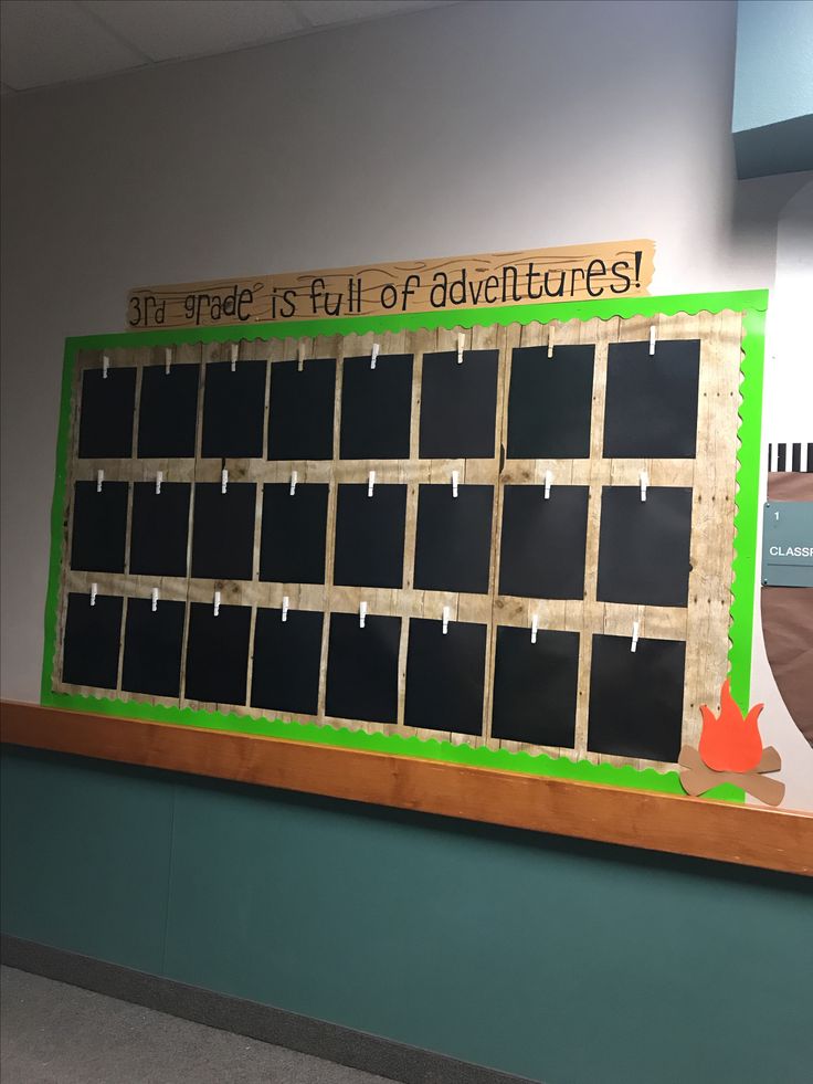 a bulletin board with writing on it in an office building or school hallway, which is decorated with green and brown strips of cardboard