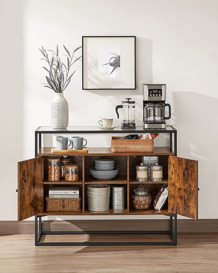 a wooden cabinet with baskets and cups on it in front of a wall mounted art