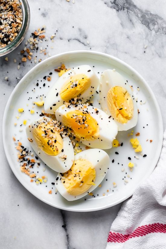 an image of boiled eggs with chives and seasoning on a plate next to a bowl