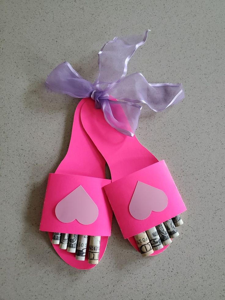 a pair of pink flip flops with hearts cut out of them, tied to a purple ribbon