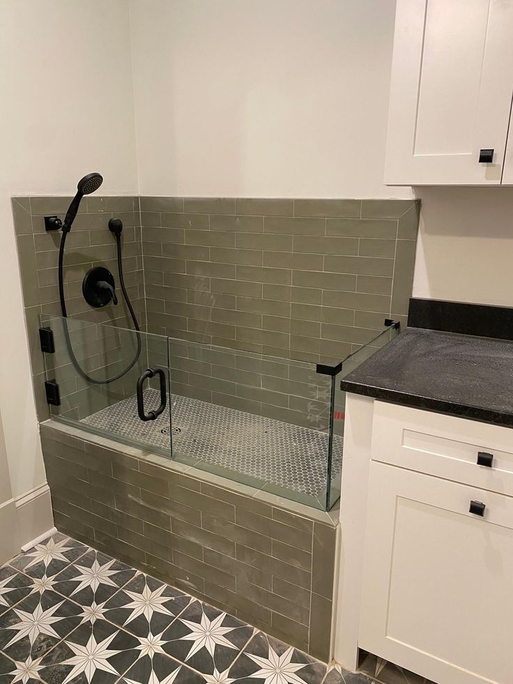 a bathroom with black and white tiles on the floor, shower head, and bathtub