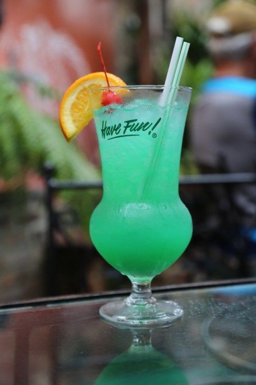 there is a green drink with orange wedges on the rim and a straw in it