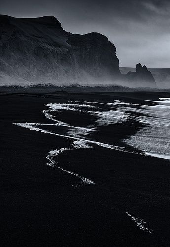 a black and white photo of an ocean beach with waves coming in from the water