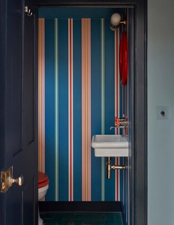 an open door leading to a bathroom with striped wallpaper on the walls and floor