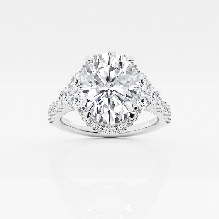 a diamond engagement ring with two side stones on the band and an oval center stone