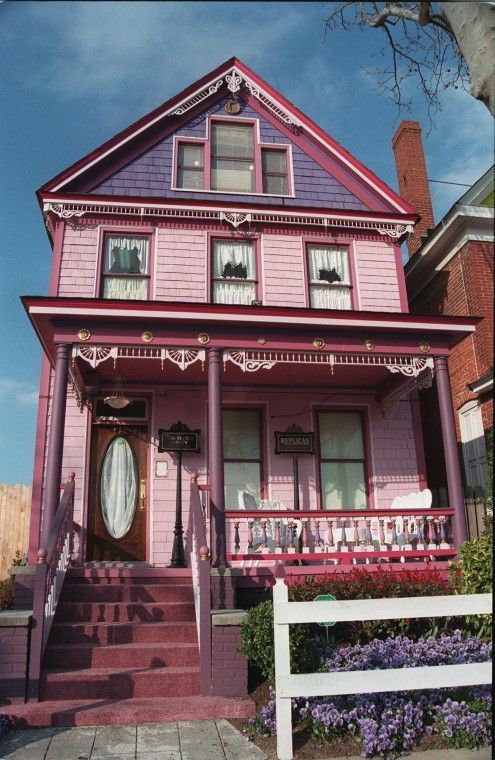 a pink house with purple trim on the front porch and steps leading up to it