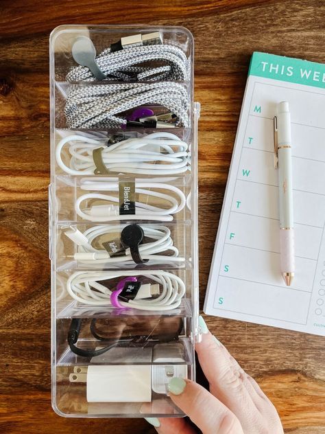 a person is holding a pen and looking at the contents in their organizer box on a wooden table