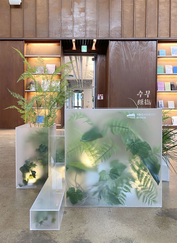 two clear vases filled with plants on top of a counter next to bookshelves