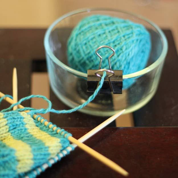 two balls of yarn sitting on top of a wooden table next to a knitting needle