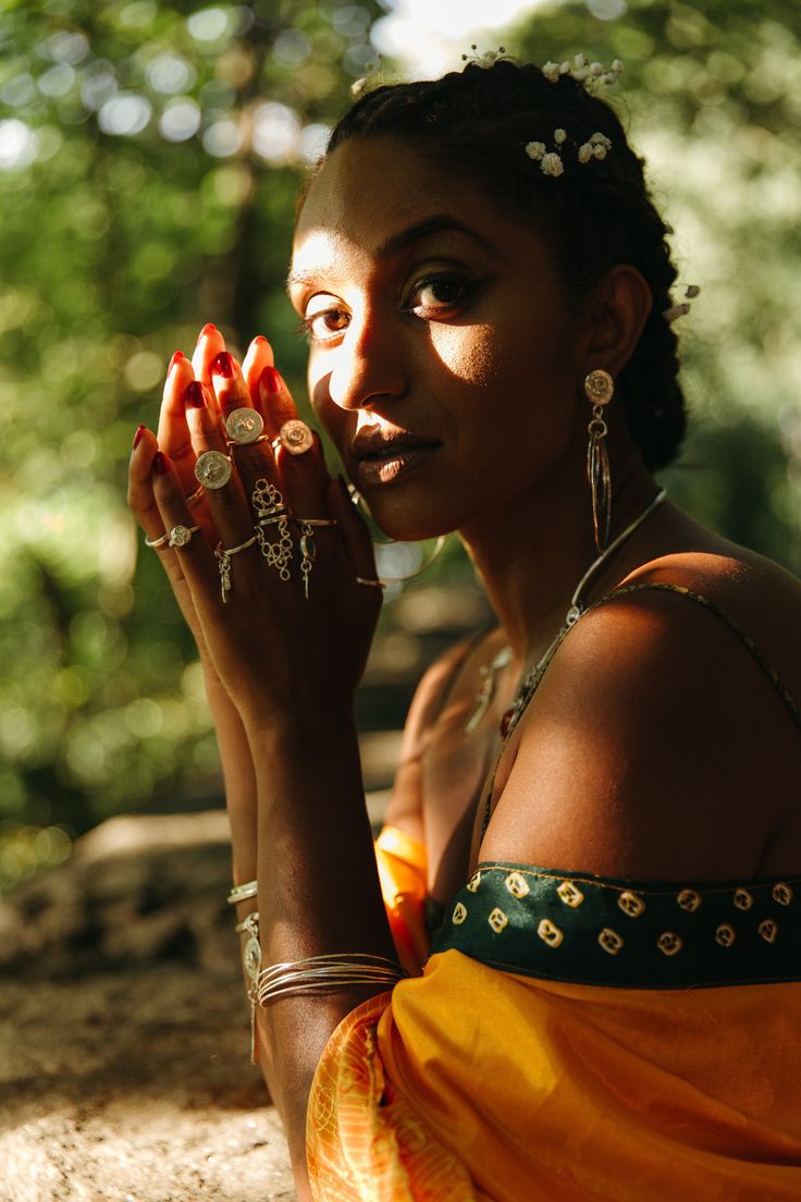 a woman sitting on the ground holding her hands to her face and looking at the camera