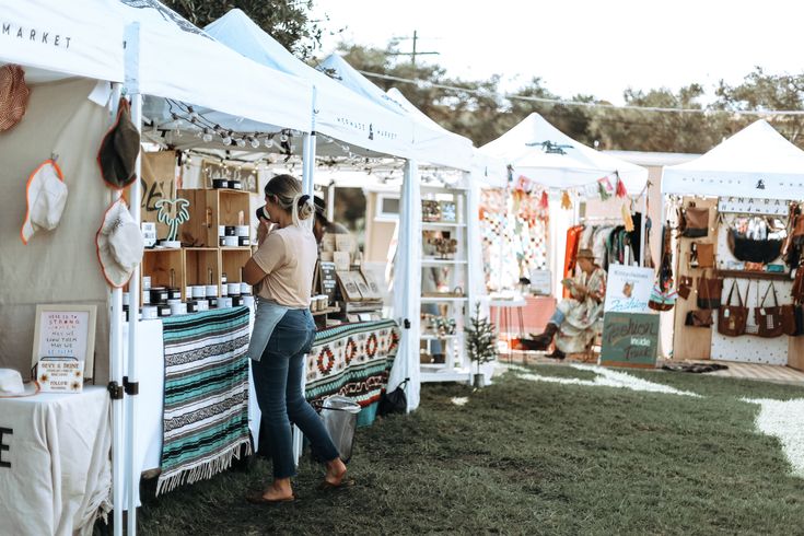 a woman standing in front of a tent selling items