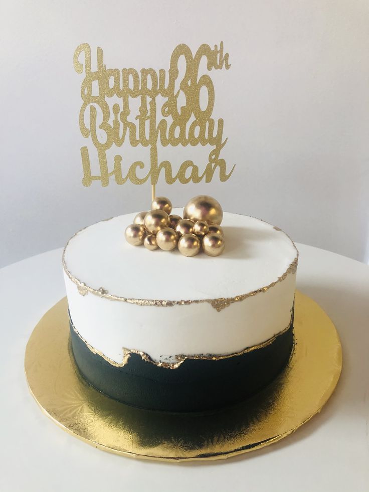 a white and gold birthday cake with two pearls on top