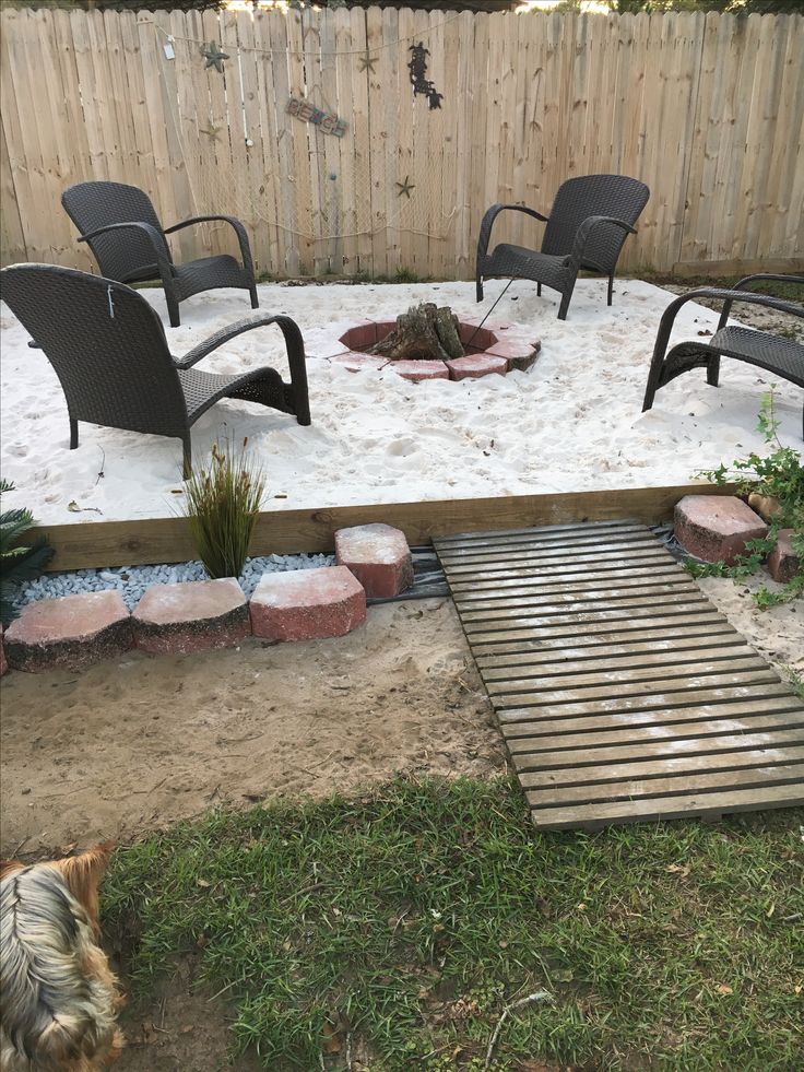 a fire pit in the middle of a backyard with chairs around it and a dog laying on the ground