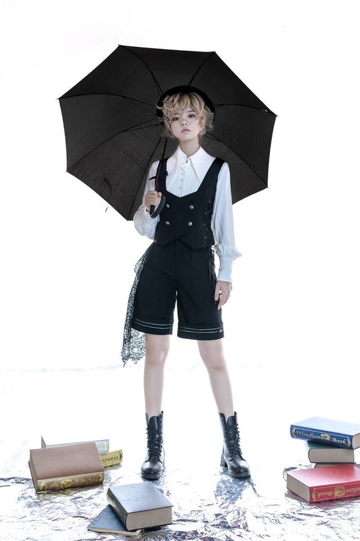 a young boy is holding an umbrella and standing in front of books on the ground