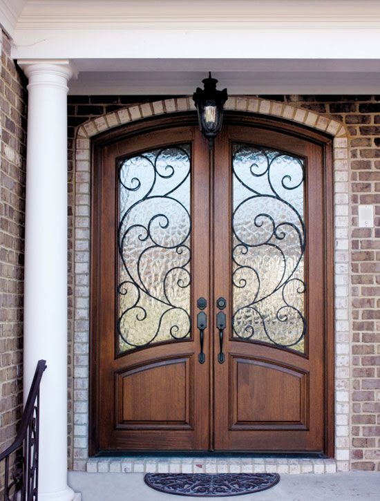 two wooden doors with glass panels and brick wall