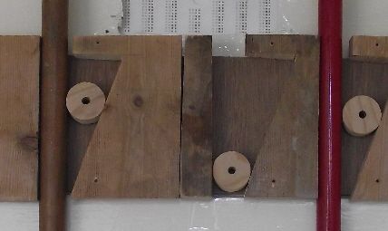 three pieces of wood with holes in the middle and two red sticks sticking out of them