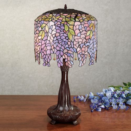 a lamp that is sitting on top of a table next to some blue and purple flowers