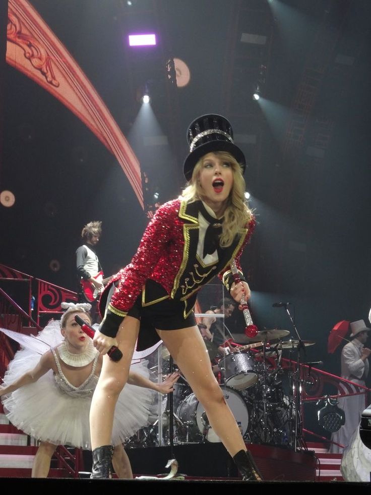 taylor swift performing on stage with dancers in the background