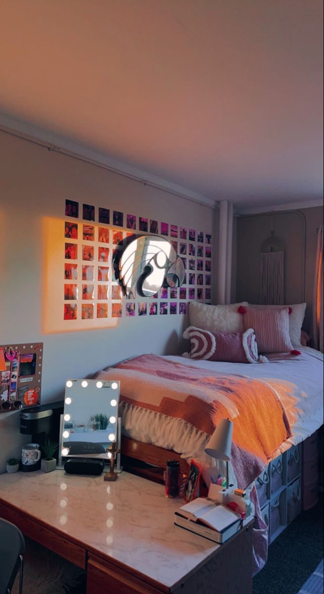 a bed room with a neatly made bed next to a desk and mirror on the wall