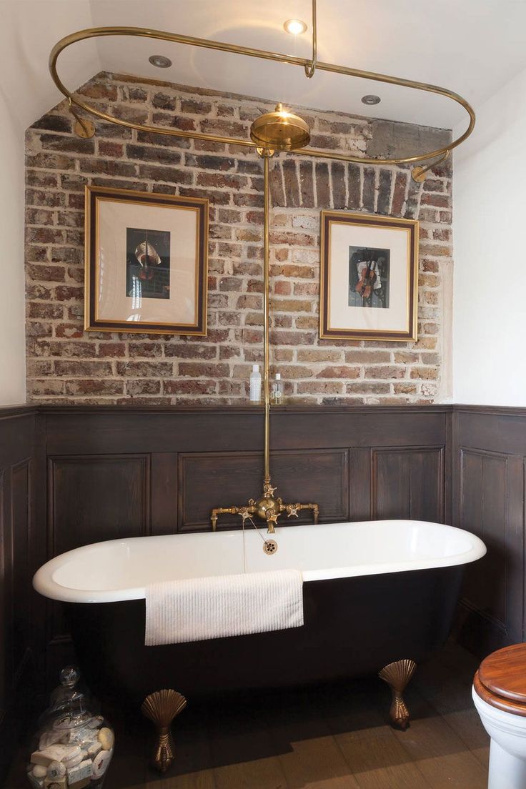 an old fashioned claw foot bathtub in a bathroom with brick wall and wood paneling