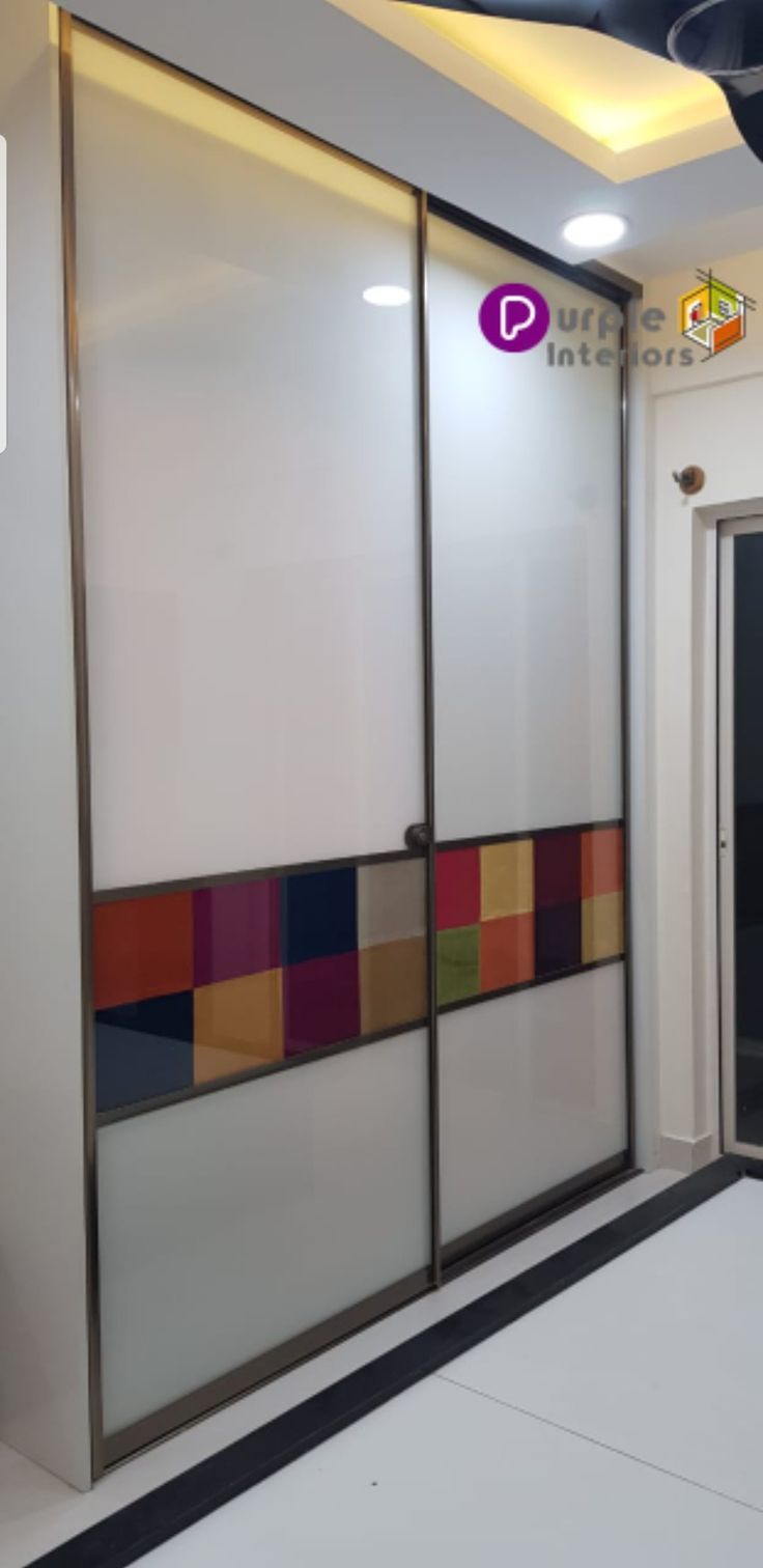 an empty room with two sliding doors and colorful tiles on the wall behind it,