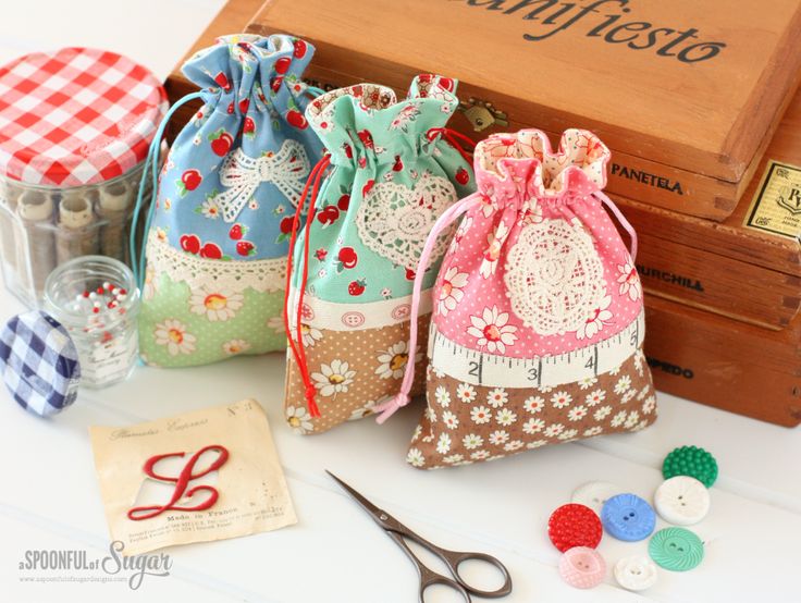 three small bags are sitting next to some sewing needles and thread spools on a table