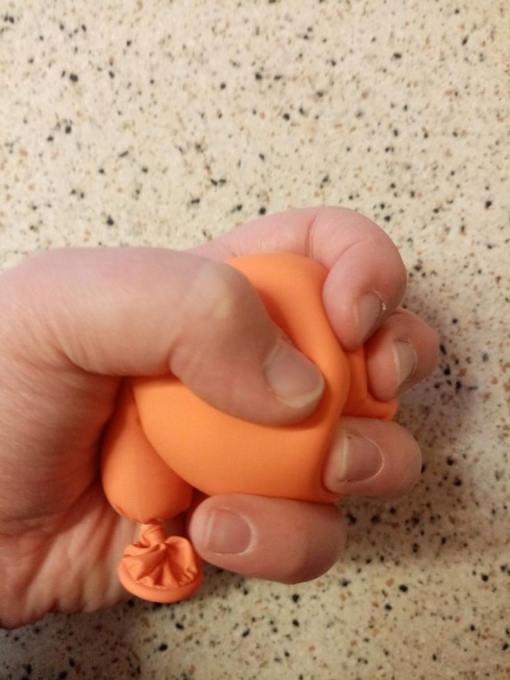 a hand holding an orange object on a table