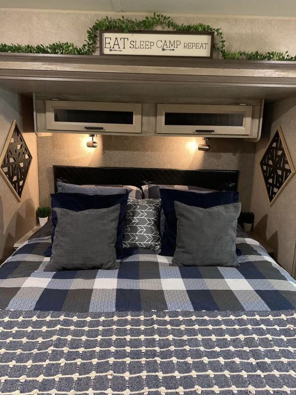 a bed with blue and white pillows in a room that has a sign on the wall above it