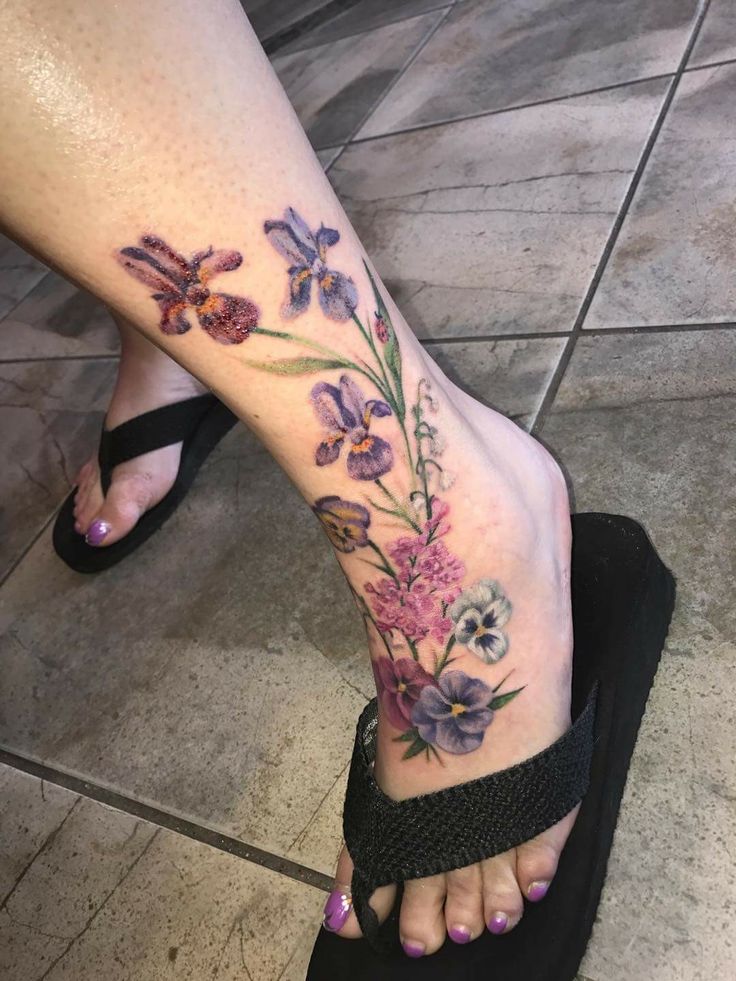 a woman's foot with flowers and butterflies on her left side, while she is wearing black sandals