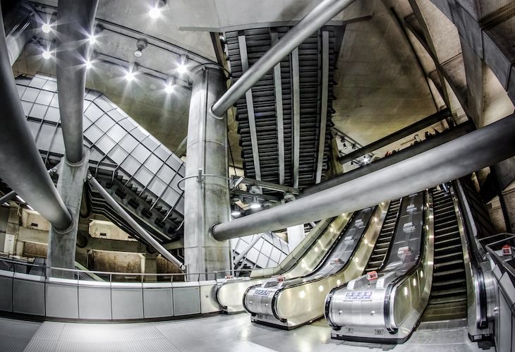 an escalator in a building with metal railings and lights on the ceiling