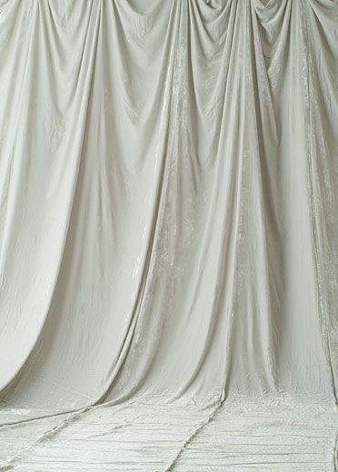 a person on a snowboard in front of a white curtained wall and floor