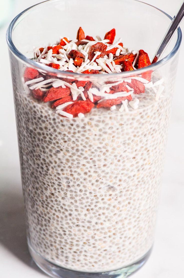 a glass filled with oatmeal topped with strawberries and coconut flakes