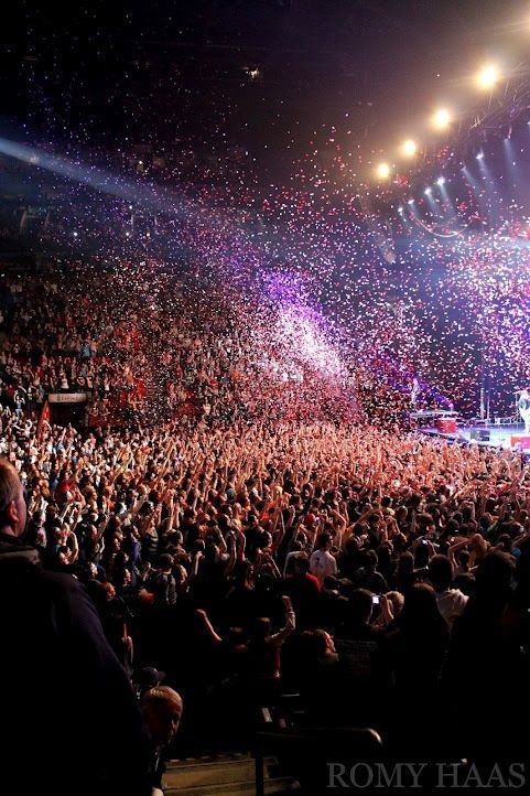 a large crowd at a concert with confetti in the air