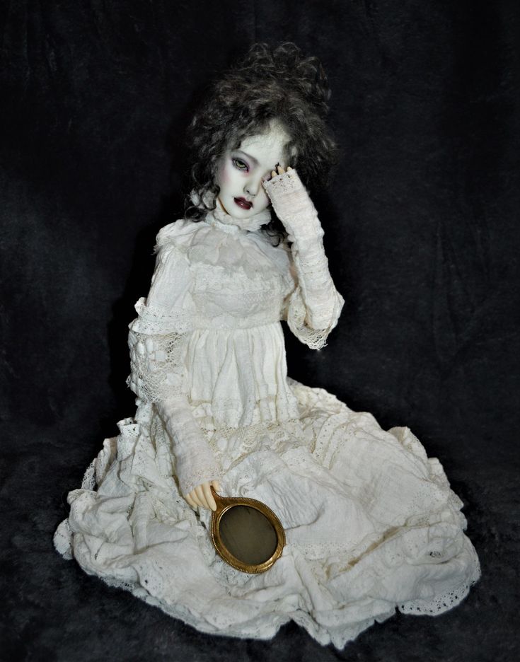 a doll is sitting on the floor with her hands to her face and holding a mirror