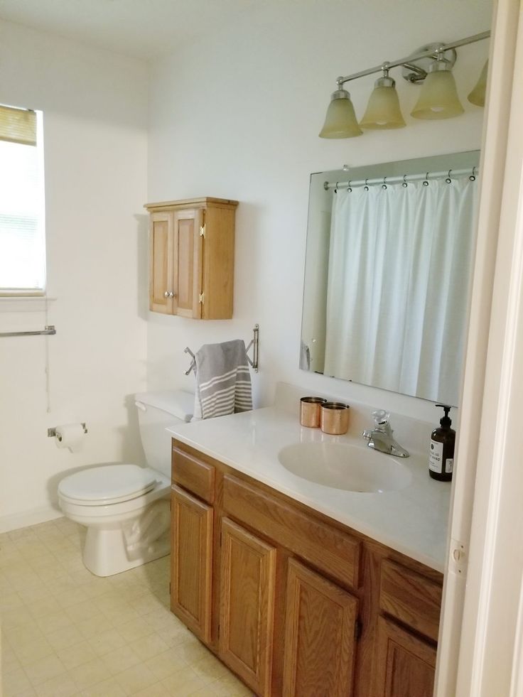 a bathroom with two sinks, a toilet and a window in the corner is shown