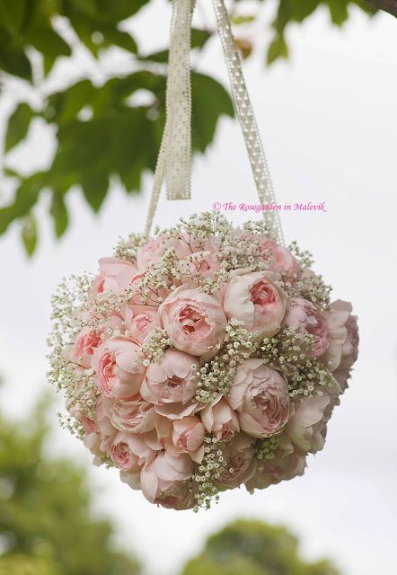 a bouquet of pink roses hanging from a tree with baby's breath in it