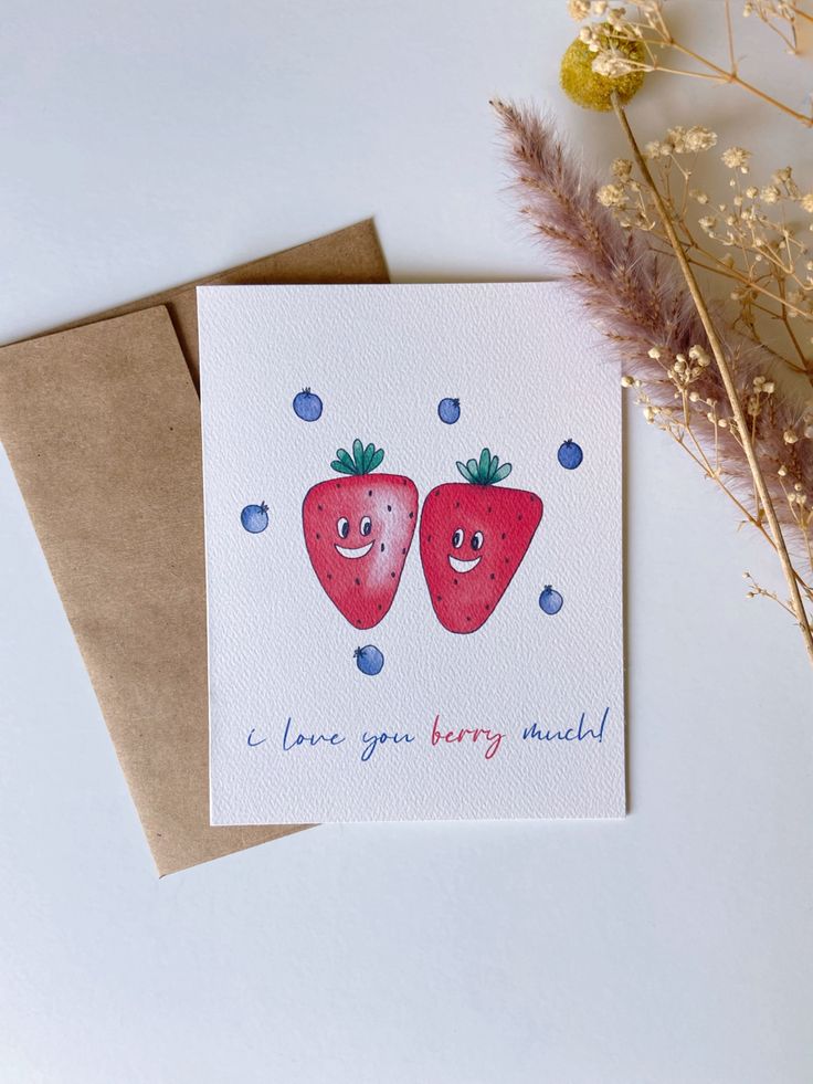 two strawberries with hearts on them are next to some dried flowers and brown envelopes