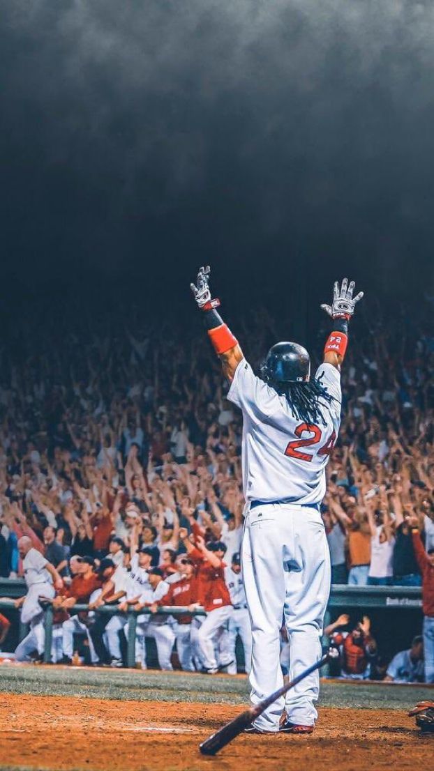 a baseball player holding his arms up in the air while standing on top of a field