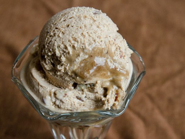 an ice cream sundae in a glass dish on a brown cloth covered tablecloth