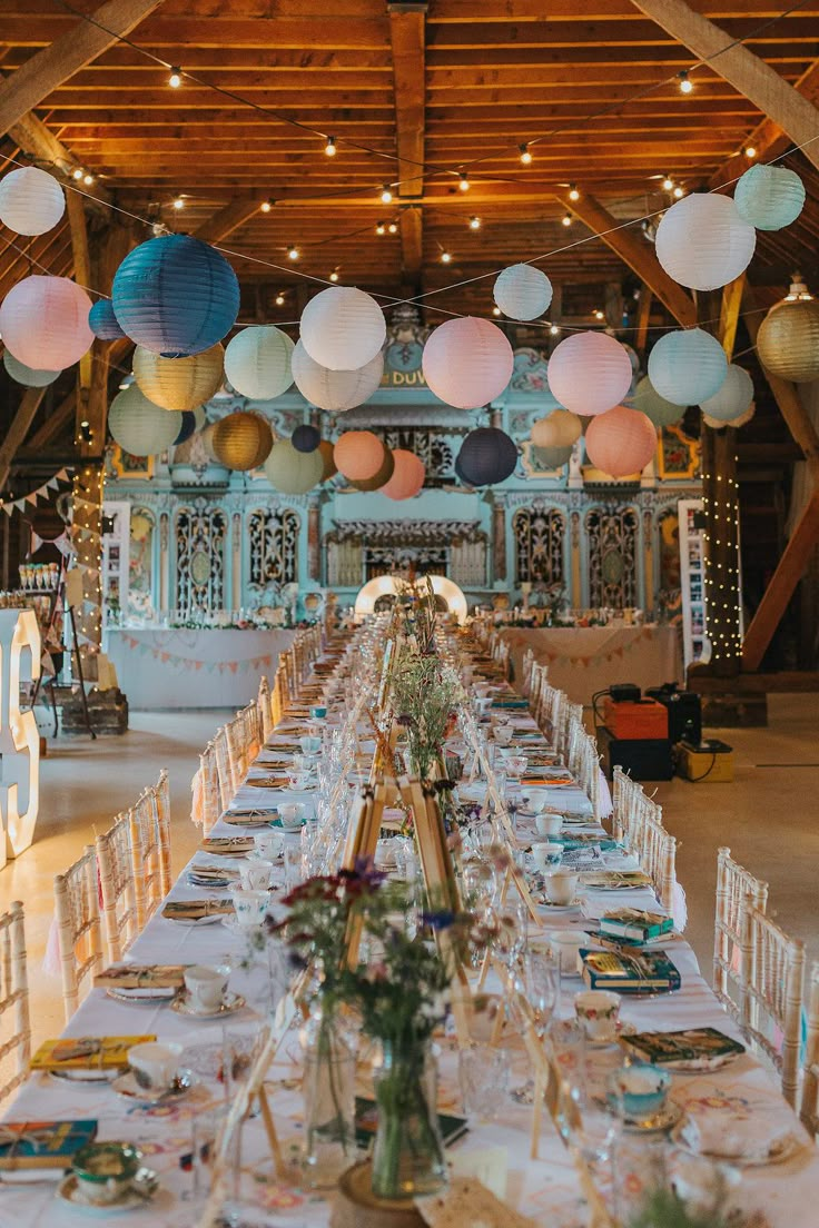 a long table is set with paper lanterns and place settings for the guests to sit down