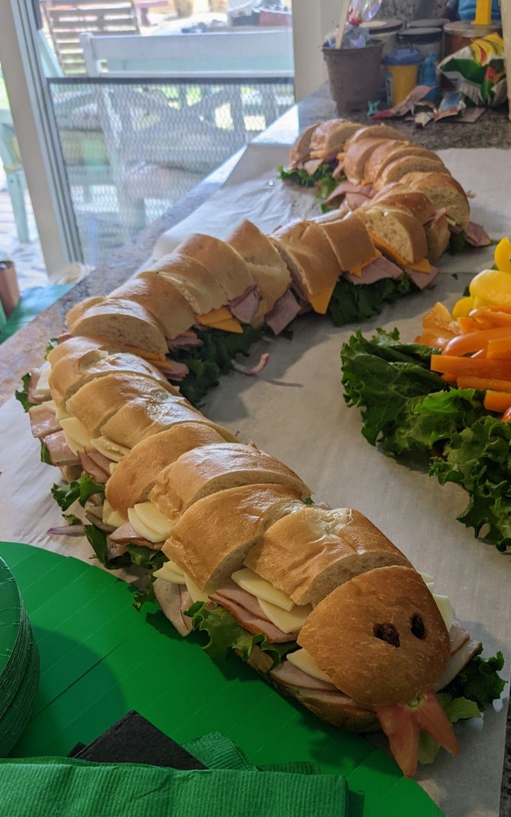 several sandwiches are lined up on a table next to carrots and other food items