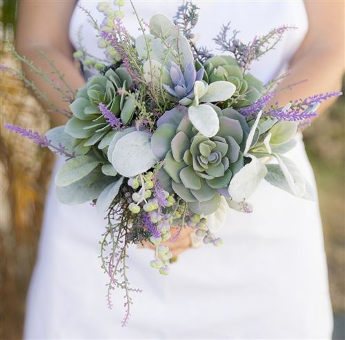 a bride holding a bouquet of succulents and greenery