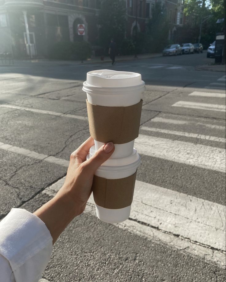 a person holding up a coffee cup on the street